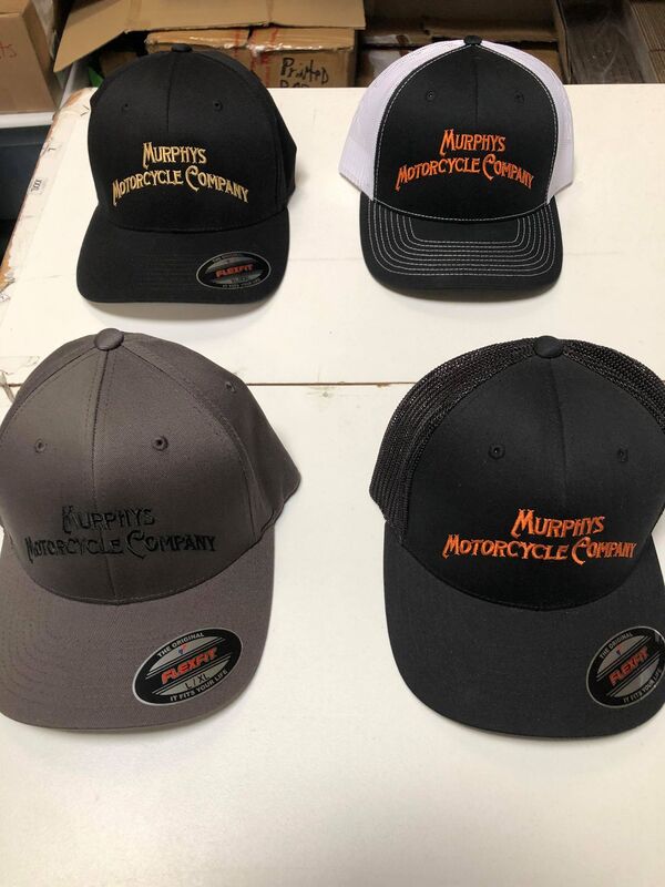 Close-up of black baseball caps with different colored brims featuring Murphy's Motorcycle Company logo.